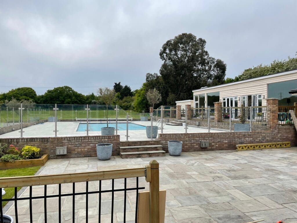 Free floating glass balustrade supplied and install around a swimming pool using 13.5mm toughened laminated glass panels